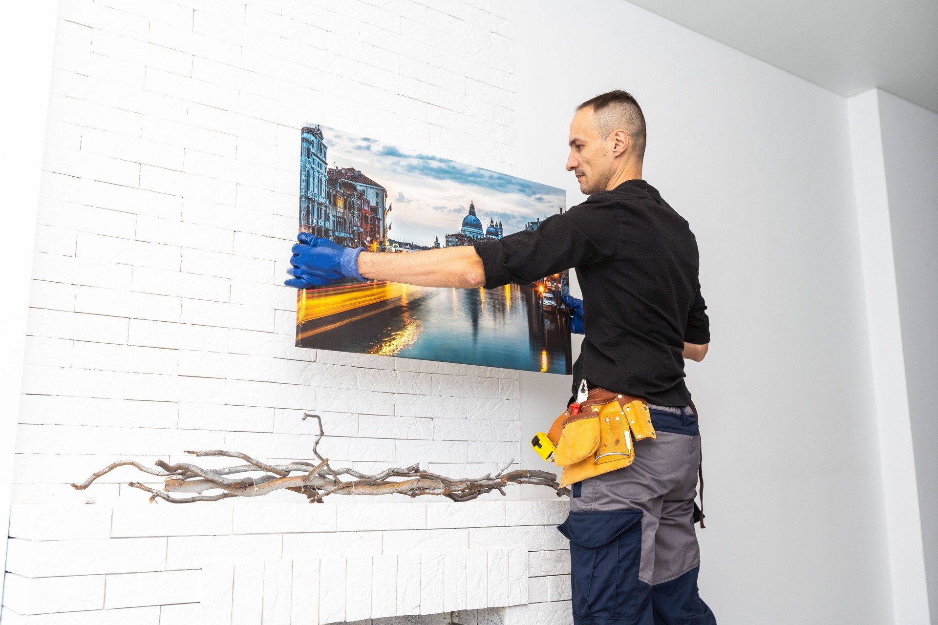 Man hanging pictures on the wall, cleaning and remodeling apartment.