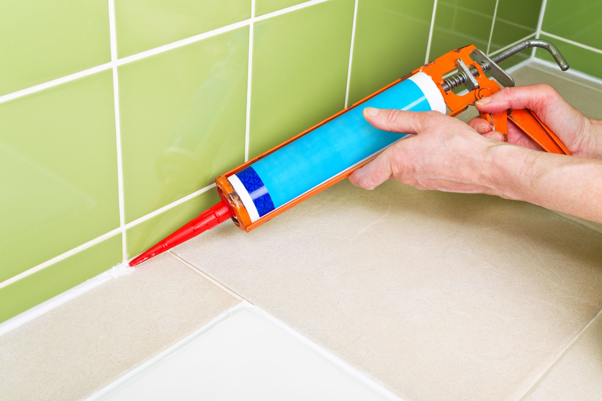 Sealing shower tiles with caulk gun